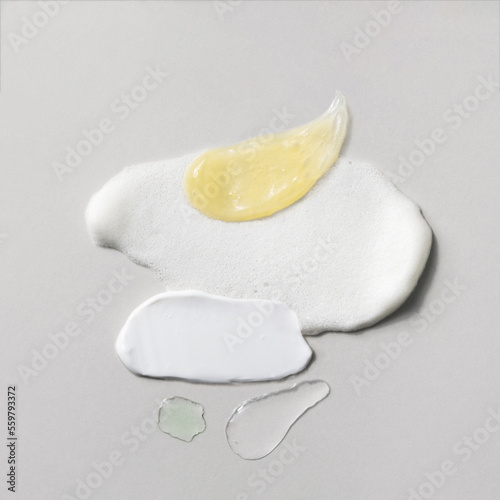 White cream, cleansing foam, yellow gel, tonic and transparent facial serum swatches. Beauty routine steps smears. Different skin care products texture. Cosmetic smudge on light grey background.