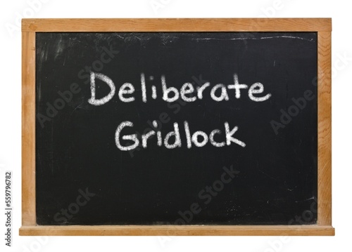 Deliberate gridlock written in white chalk on a black chalkboard isolated on white