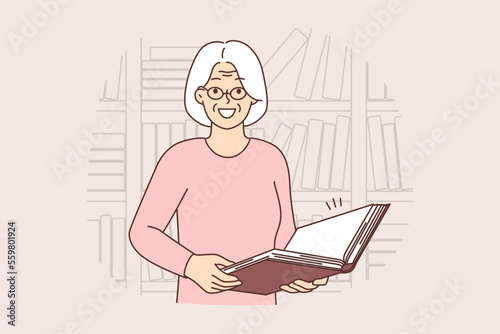 Smiling old woman with book in library 
