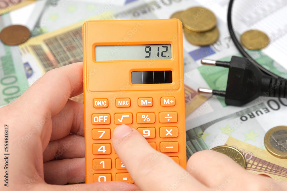 Person Counting and Calculate Cost Money of Electricity and Heating Bill. Electric Cap, Light Bulb and Euro Banknotes on the Background. Increase in the Cost of Electricity. Price Hike. Energy Crisis Person Counting and Calculate Cost Money of Electricity and Heating Bill. Electric Cap, Light Bulb and Euro Banknotes on the Background. Increase in the Cost of Electricity. Price Hike. Energy Crisis