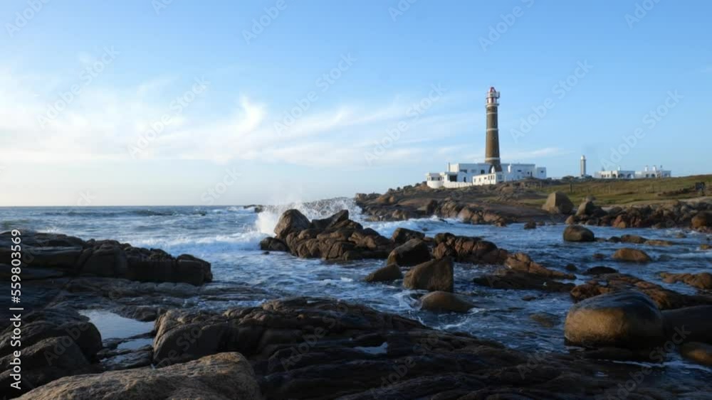 Super camara lenta olas chocando rocas y faro de fondo 