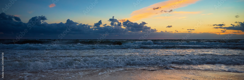 Sea coastline with waves. Baltic sea against dramatic cloudy sky at sunset. Panoramic nature landscape