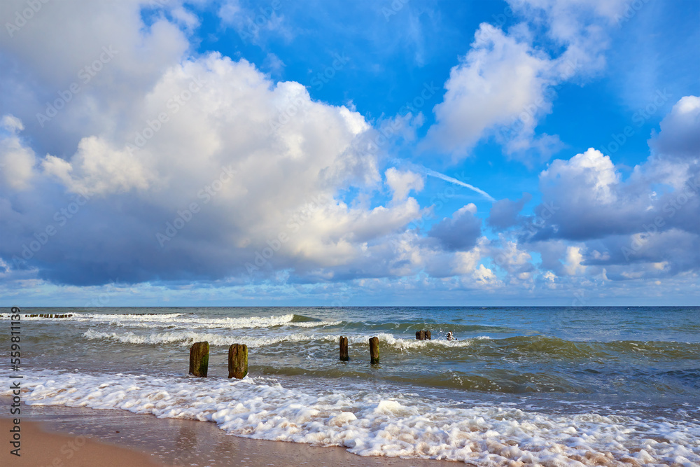 Sea coastline with waves at summer day. Baltic sea beach against beautiful cloudy sky. Panoramic nature landscape