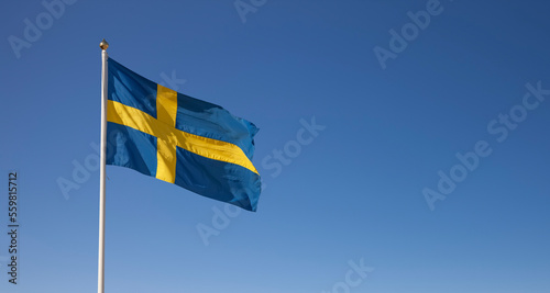 Schwedische Nationalflagge im Wind wehend vor blauem Himmel