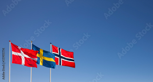 Dänische, Schwedische und Norwegische Nationalflagg im Wind wehend vor blauem...