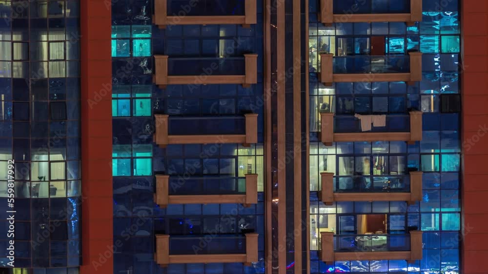 Night aerial view of apartment building glass window facade with illuminated lighted workspace rooms timelapse. Glowing light in skyscraper with balconies Night aerial view of apartment building glass window facade with illuminated lighted workspace rooms timelapse. Glowing light in skyscraper with balconies