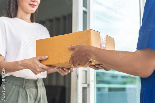 Wallpaper Mural Close up delivery man hands wearing blue uniform send a cardboard box to customer in front of the customer's house with sunset flare background. Torontodigital.ca
