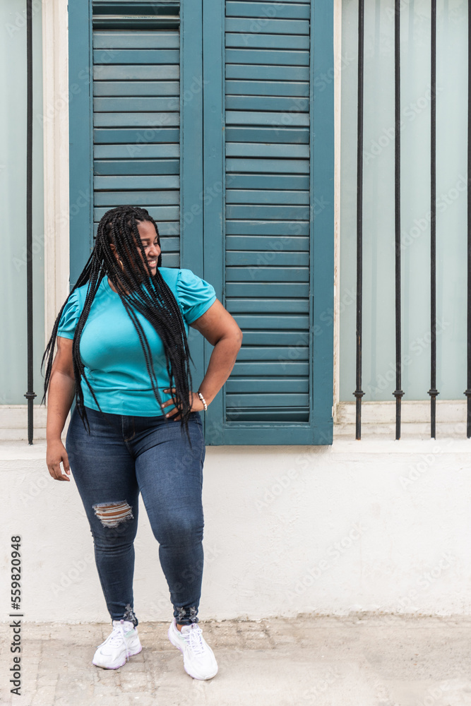 expressive woman with long braids dancing in the city very happy