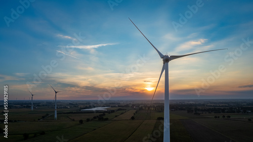 Wind farm with wind Turbine in a rural area against the sunset seen from an aerial view shot by a drone. High quality photo