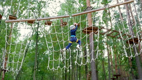 Climbing adventure park, high school teenage boy enjoying activity in climbing park on track wearing mountain helmet and protective gear