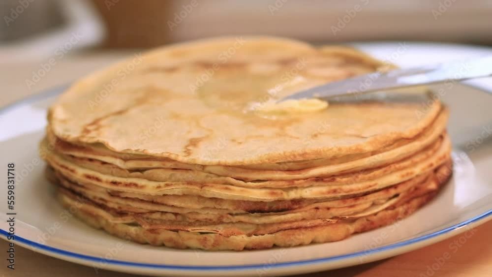 Buttering hot freshly baked crepes. Cooking pancakes at home. Delicious food, breakfast