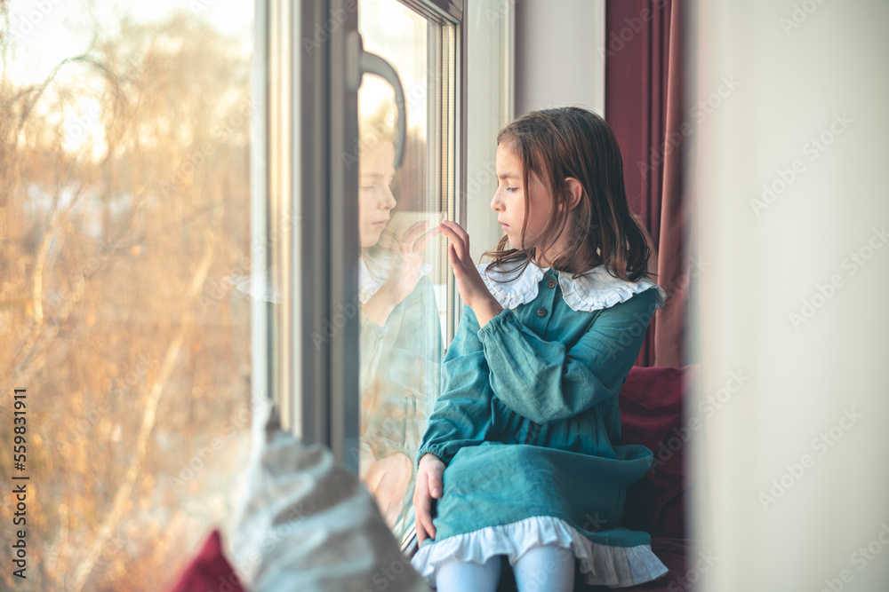 a pensive cute girl sits and looks out the window a pensive cute girl sits and looks out the window