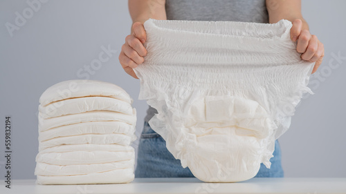 Foto A woman chooses an adult diaper from a pile