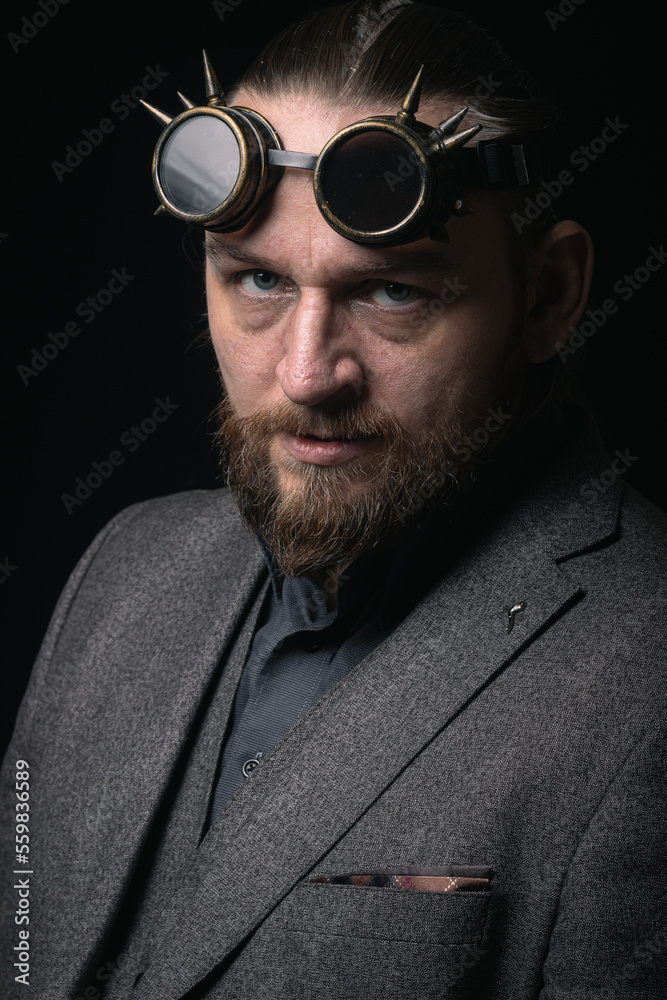 Obraz premium charismatic man in a classic suit and steampunk goggles on a black background stylish Portrait
