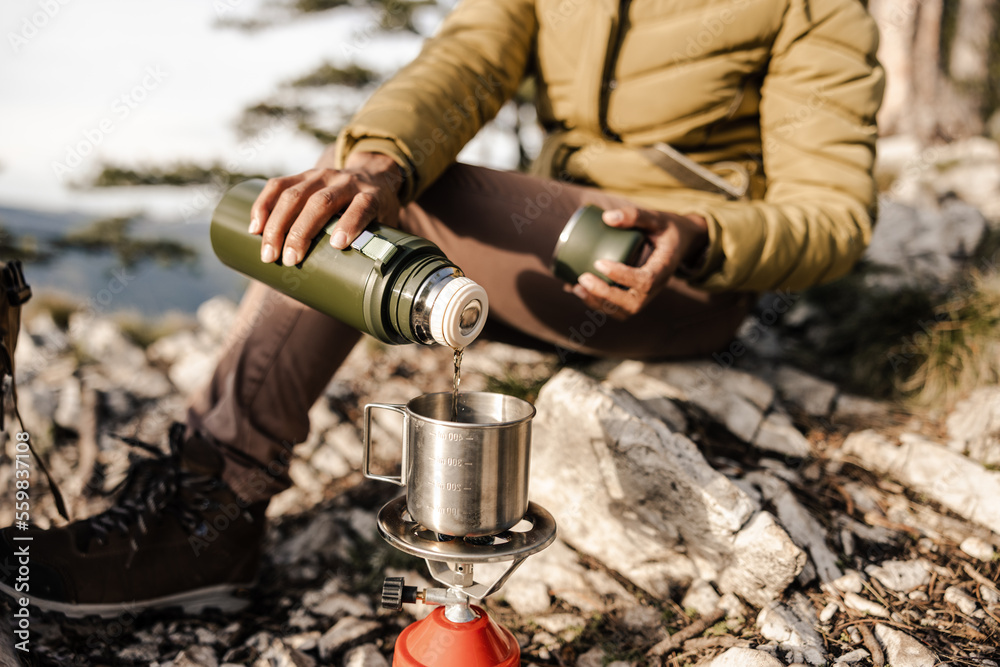 Fototapeta premium Woman Preparing Tea While Hiking On Mountain