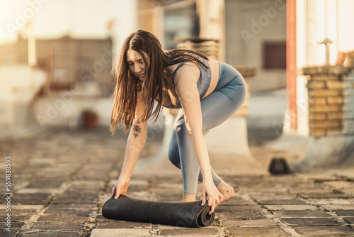 Woman Rolling Up Yoga Mat And Preparing To Outdoors Training