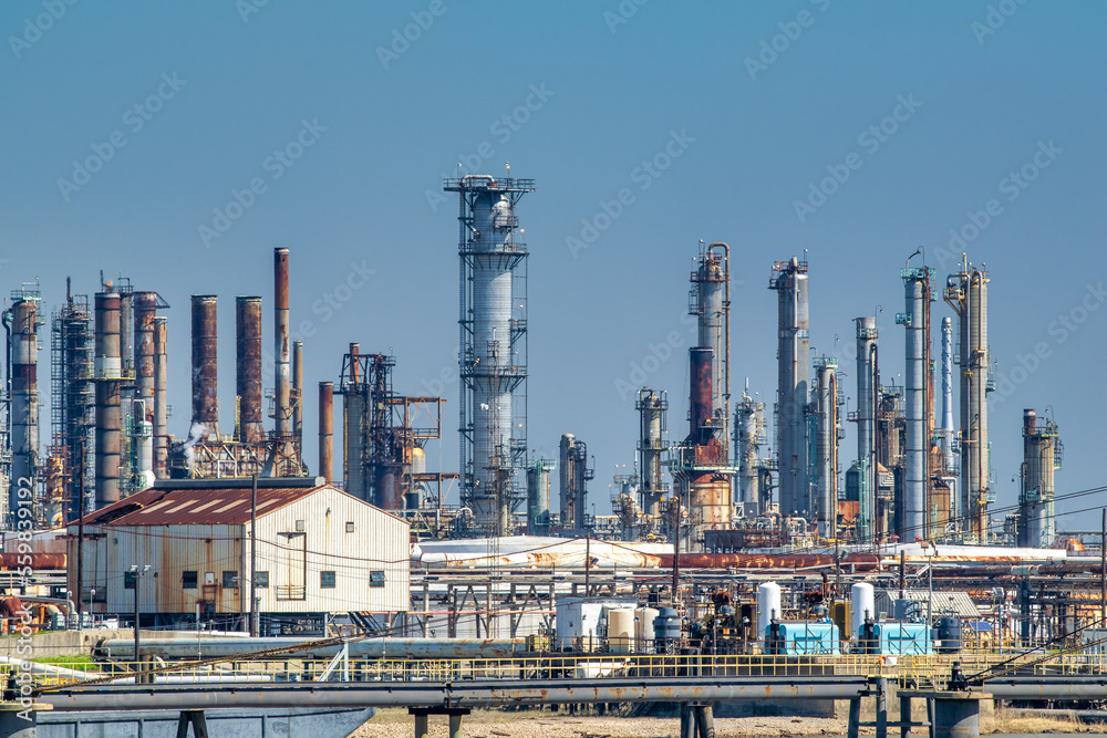 Oil refinery industry view details of pipes with valves in a large refinery isolated on blue sky