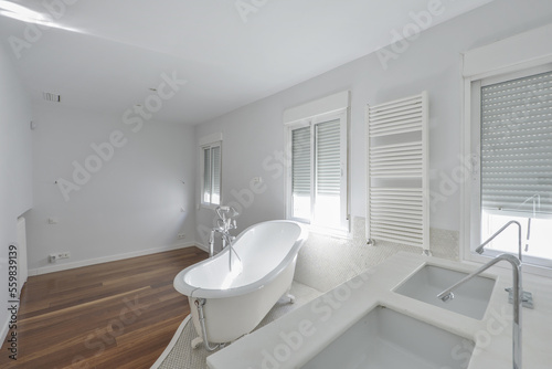 Bathroom with a wall covered in gresite-type tile  a two-bowl white marble sink and a bathtub on the surface with legs