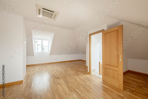 Spacious room in the attic floor of a single-family home with skylights  oak flooring  air conditioning on the ceiling and aluminum radiators