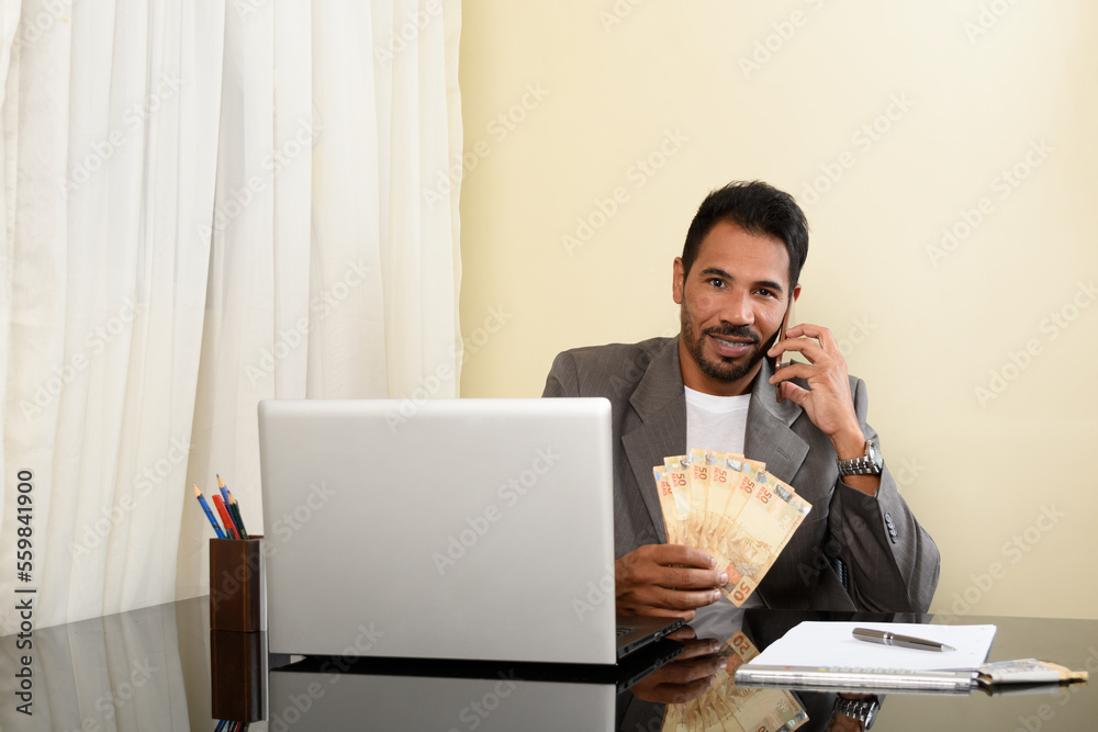 businessman looking at camera and holding money, sitting in his office