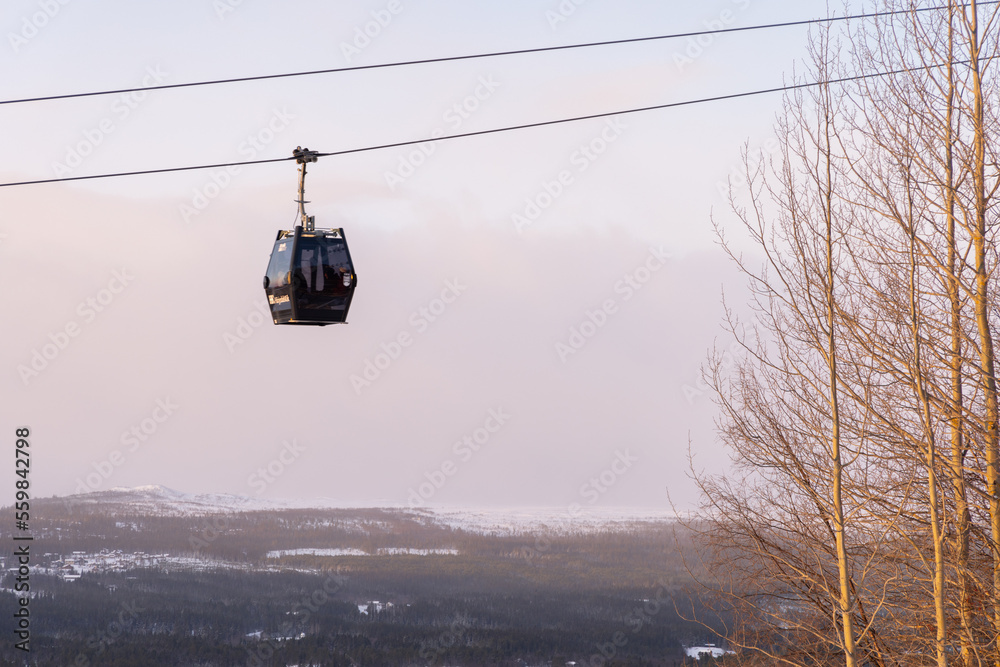 Beautiful ski slope in Funasdalen, Sweden with ski lift, gondola going up the hill surrounded by forest on a sunny winter day. Skiing resort in Sweden, Funasdalen covered in snow