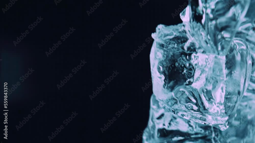 Ice cubes falling down in glass, macro extreme close up. Ice flying right at us, bottom view, under icy. Super slow motion 1000 fps pour fall green ice cubes in empty glass. Pov view throw ice cubes