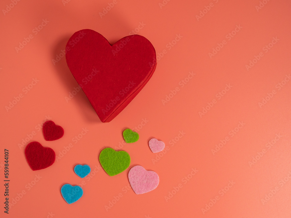 Heart of different colors on a pink background.