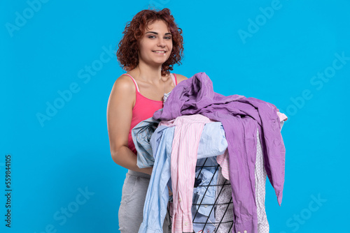 A smiling girl holds in her hand a basket full of washed and dried clothes.