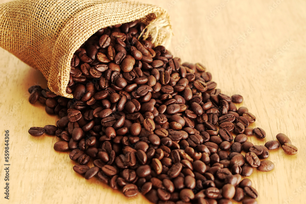 Fototapeta premium Sack of coffee beans on wooden background