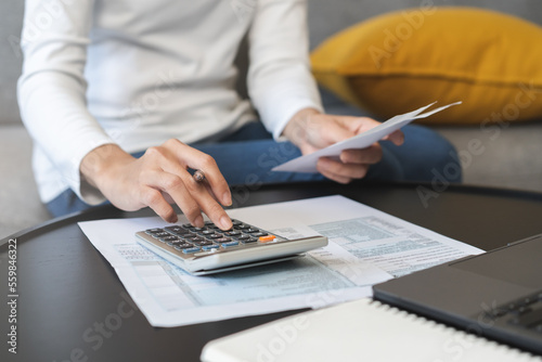 Deduction planning concept. Asian young woman hand using calculator to calculating balance prepare tax reduction income, cost budget expenses for pay money form personal Individual Income Tax Return. photo
