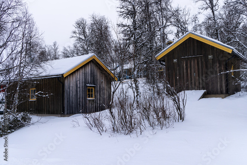 Beautiful little wooden mountain houses, huts surrounded by forest on a sunny winter day. Skiing resort in Sweden, Funasdalen covered in snow © boumenjapet