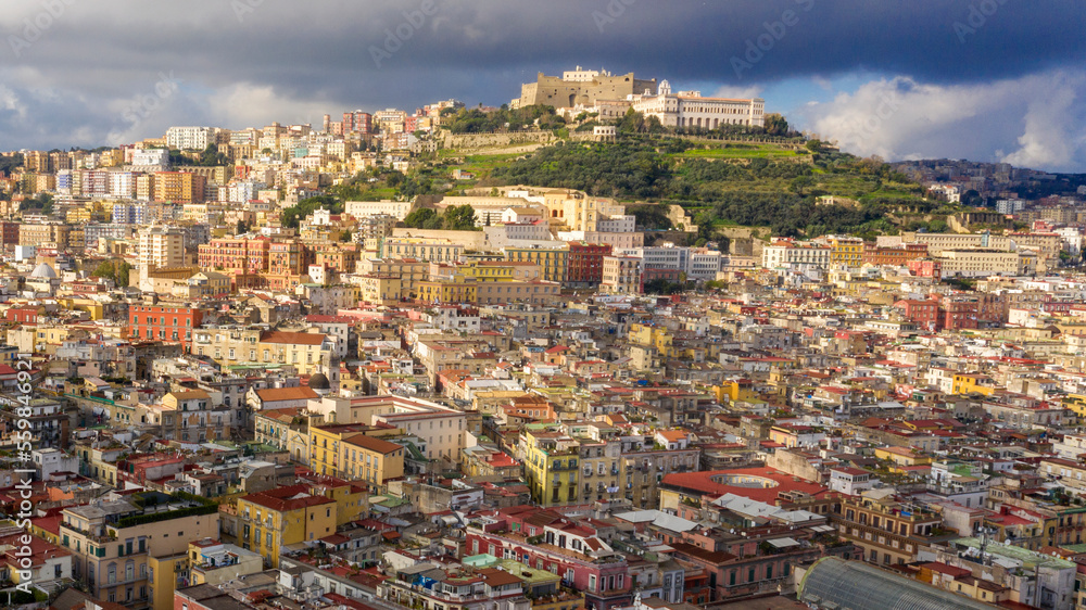 Aerial view of Vomero hill and Castel Sant'elmo from the historic center of Naples, Italy. The sky is cloudly.