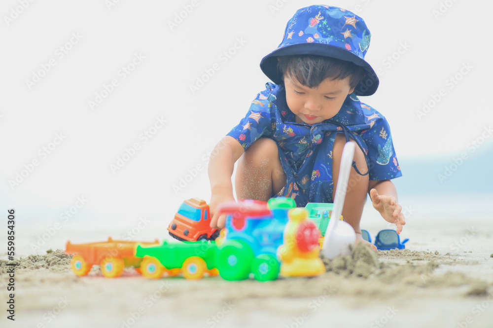 kid playing with sand on the beach by the sea. holidays with children near the ocean kid playing with sand on the beach by the sea. holidays with children near the ocean