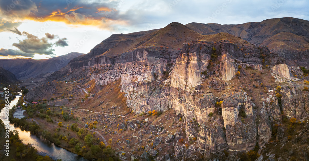 Dramatic aerial view to Vardzia cave city with paravani river and sunset in the background, Travel and sightseeing in Georgia.Unesco sites in caucasus. 2020