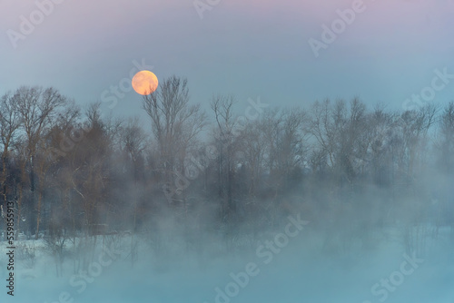 Winter morning landscape with river and fog on water, forest and moon in the sky. Christmas sketch.