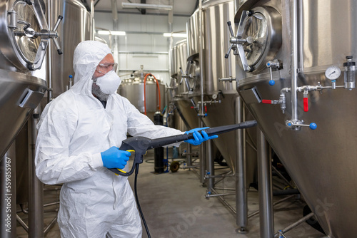 Fotografiet Experienced beer tech cleaning and sanitizing the brewing equipment