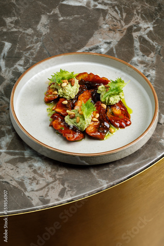 Grilled and glazed eel with guacamole  served on plate in restaurant