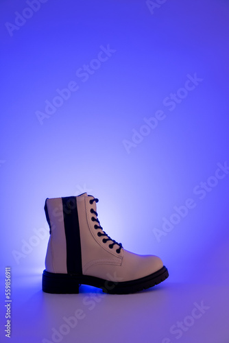 Women white boot side view on a purple light effect background.