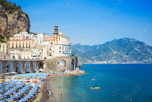 summer Atrani beach with blue umbrellas and sea water, Amalfi, Italy