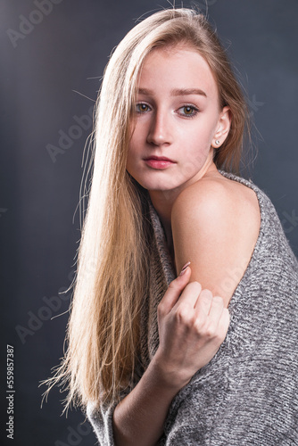Portrait of a young beautiful blonde girl in gray sweater
