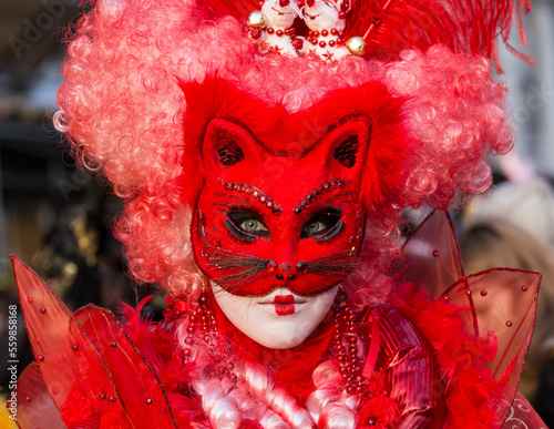 ritratto verticale di donna con maschera rosso fuoco e orecchie da gatto, tulle e vestito rosso
