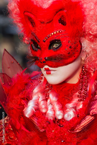 ritratto verticale di donna con maschera rosso fuoco e orecchie da gatto, tulle e vestito rosso photo