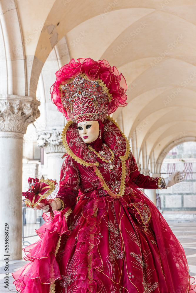 donna in costume di carnevale rosso, inserita in un sottoportico di palazzo ducale, figura intera, bouquet nella mano sinistra
