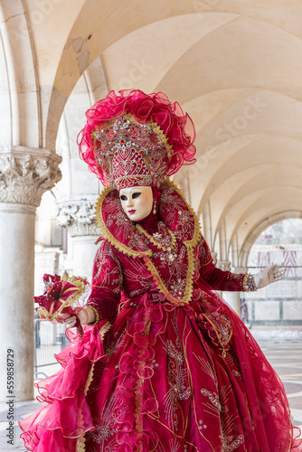 donna in costume di carnevale rosso, inserita in un sottoportico di palazzo ducale, figura intera, bouquet nella mano sinistra © frescofb