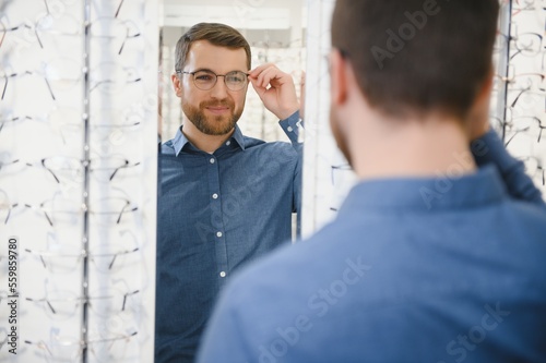 Shot of a handsome bearded man trying on new glasses at the eyewear store.Man buying glasses.Health, eyesight, vision, fashion, shopping