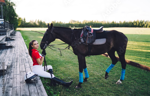 Horsewoman holding horse by reins in farmland