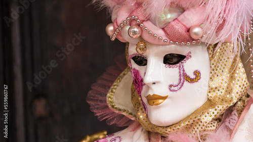 ritratto orizzontale di maschera di carnevale a venezia, spazio per testo a sinistra del frame, tinte calde photo
