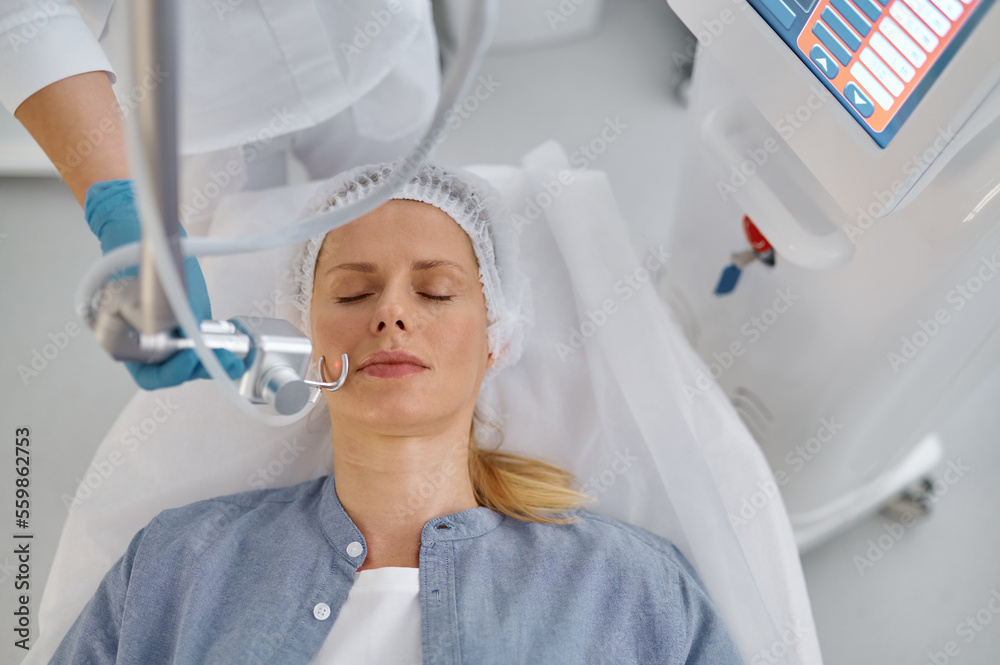 Woman getting laser face cleaning cosmetic procedure in beauty salon Woman getting laser face cleaning cosmetic procedure in beauty salon