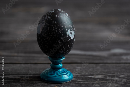 Easter egg on decorative blue stand on a wooden background