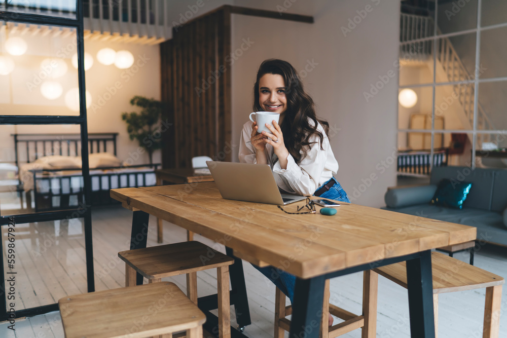 Smiling woman enjoying hot drink during remote work Smiling woman enjoying hot drink during remote work